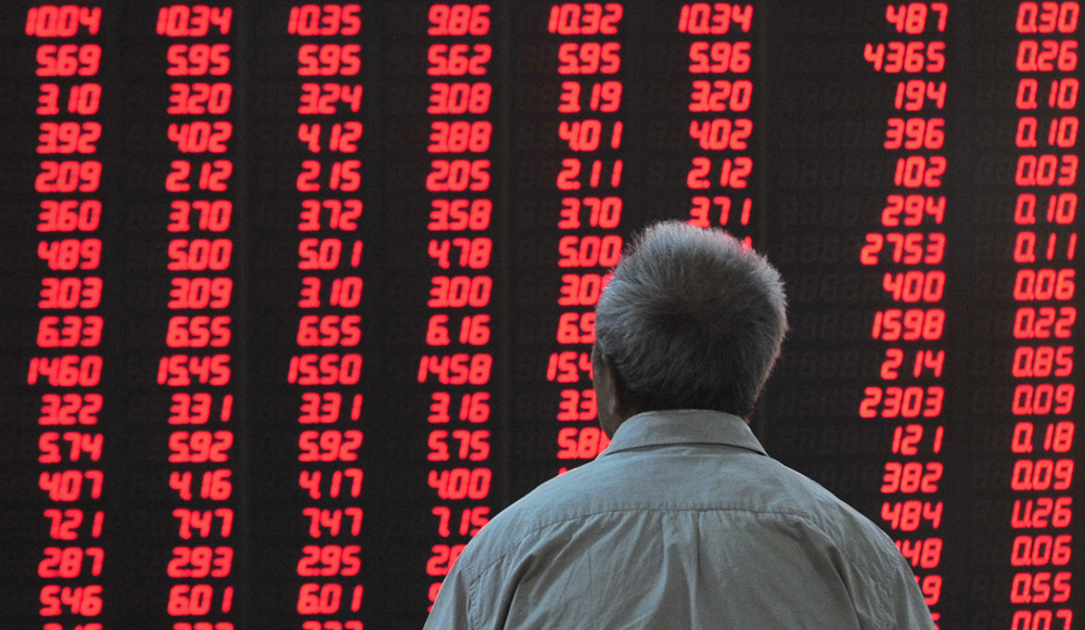 An investor looks at an electronic board showing the stock information at a brokerage house in Hefei